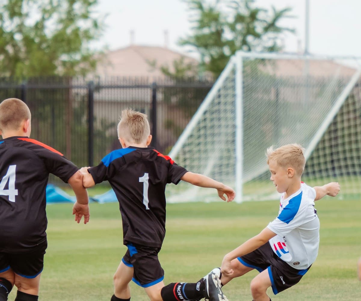 Young athletes reaching for the ball in a youth soccer match